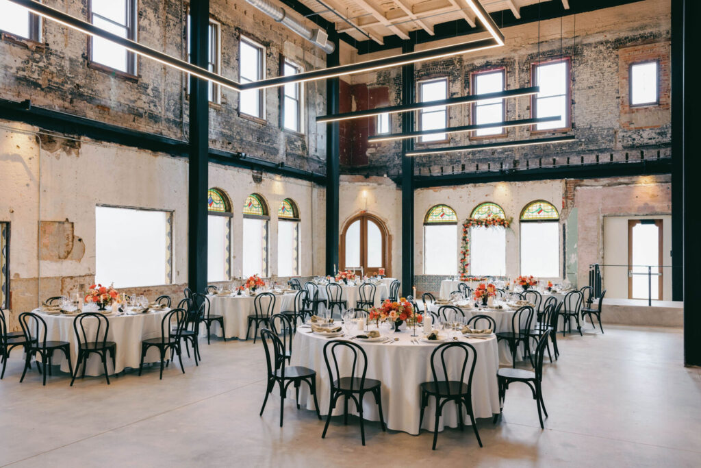 Two-story event venue in Tampa, FL with round tables and exposed brick wall