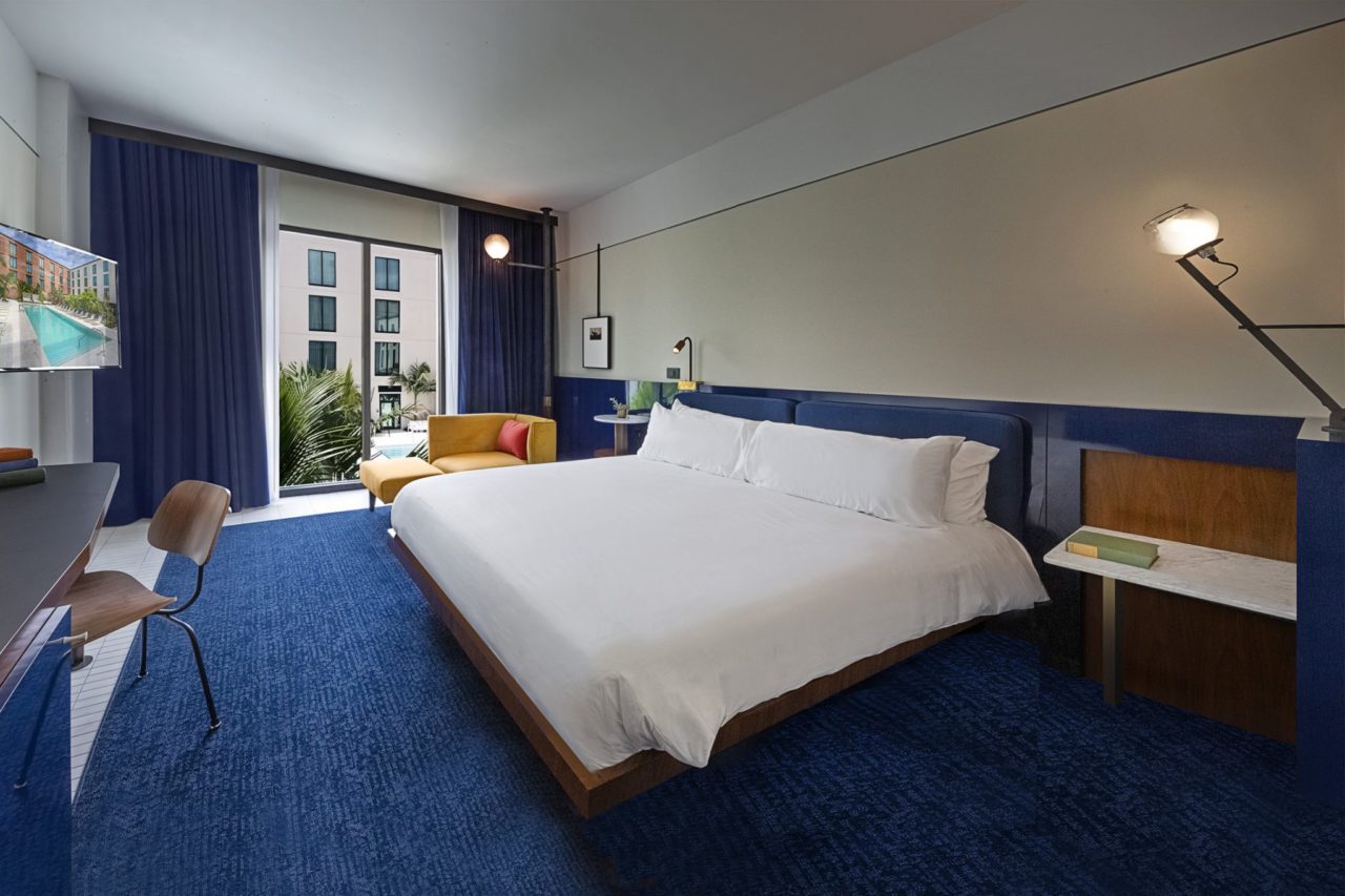 White king bed in a room with blue floors and drapes at our Ybor City, FL hotel