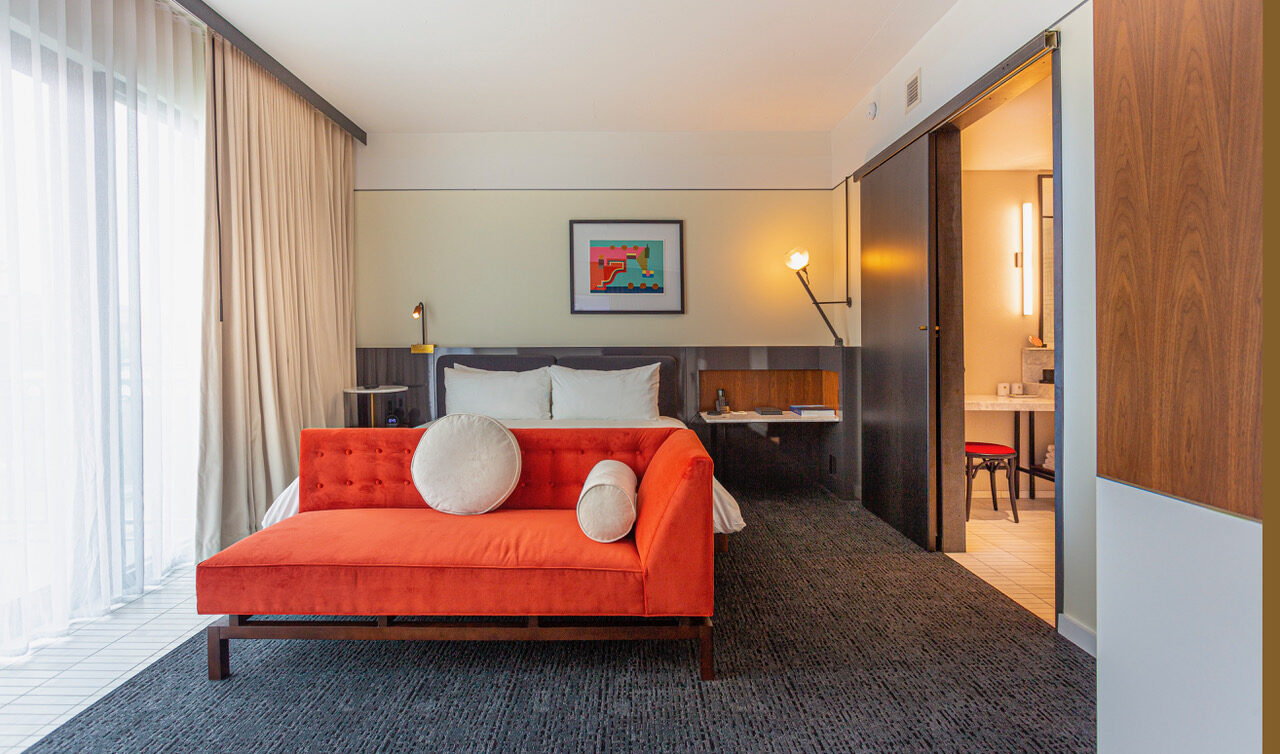 Florida Suite hotel room with king bed & and large orange sofa.