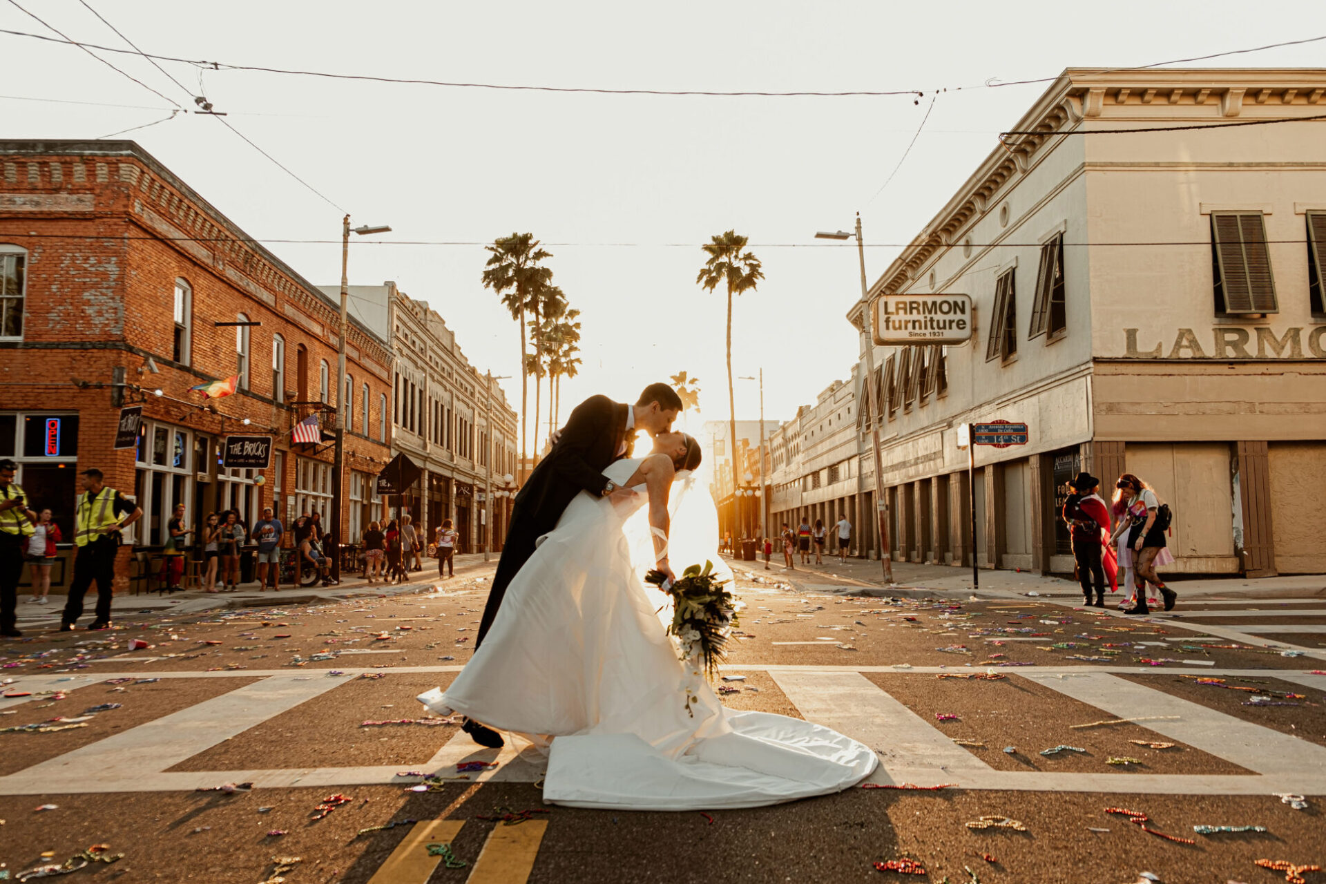 A couple in wedding atire standing in the street sharing a kiss