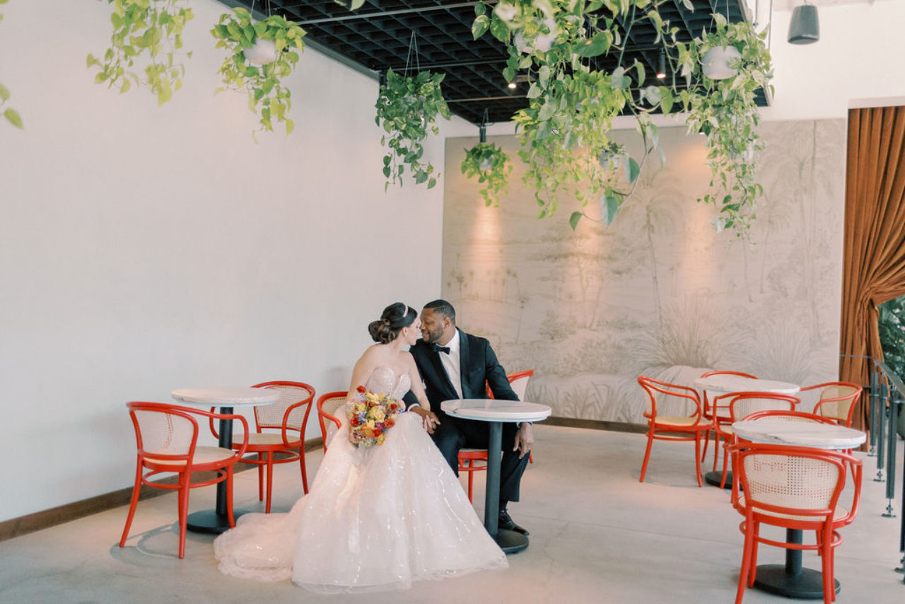 Wedding couple facing one another while sitting on our hotels red dining chairs in Tampa, FL