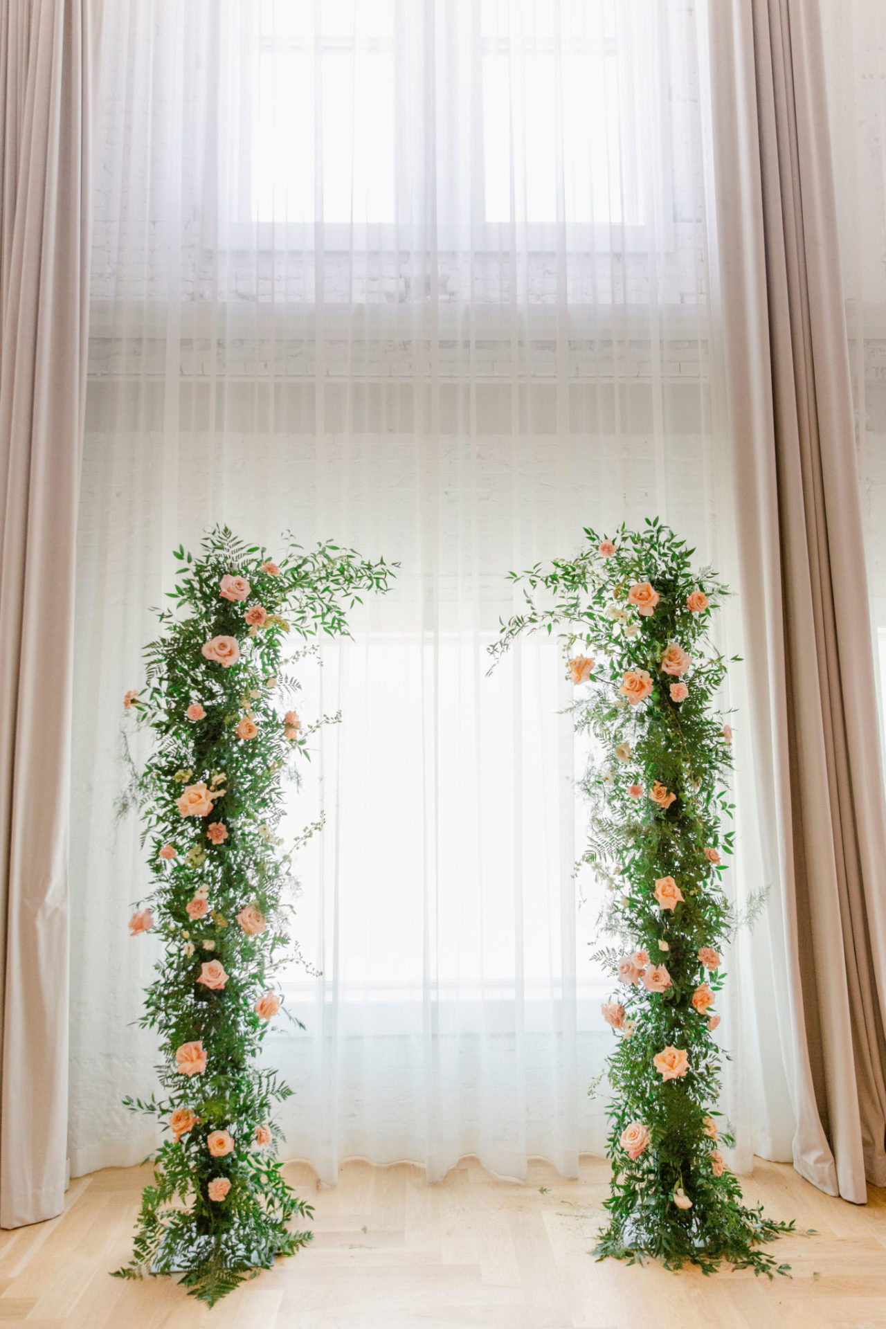 Two arbors with pink roses in front of a sheer white curtain
